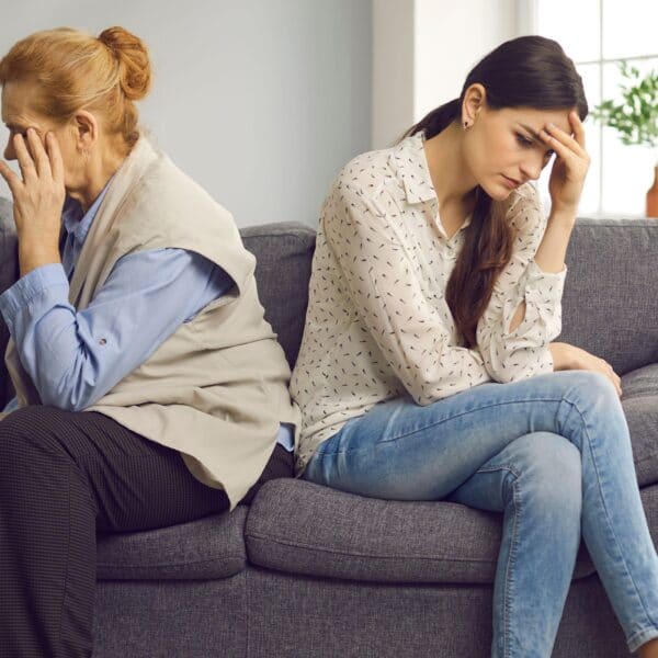 mum and daughter sit looking away from each other scaled