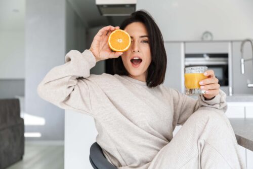woman holds half an orange to her eye