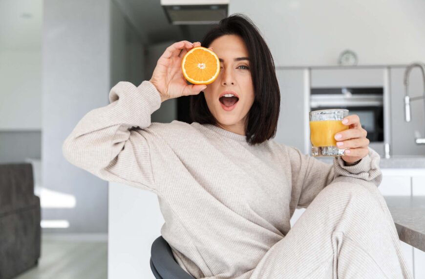 woman holds half an orange to her eye