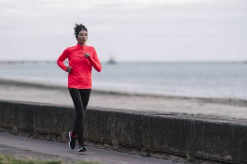 woman runs by sea wall