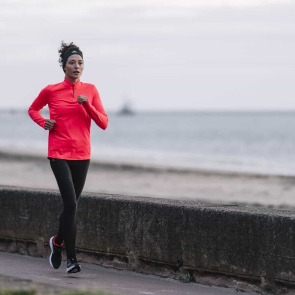 woman runs by sea wall