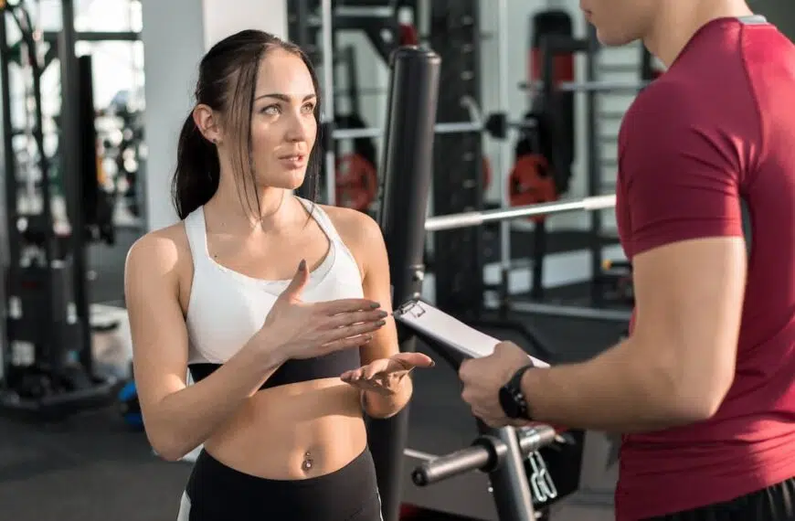 young woman talking to personal fitness coach in modern gym e1645028424321