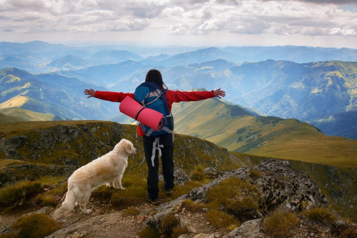 Hiker with dog at top of mountain