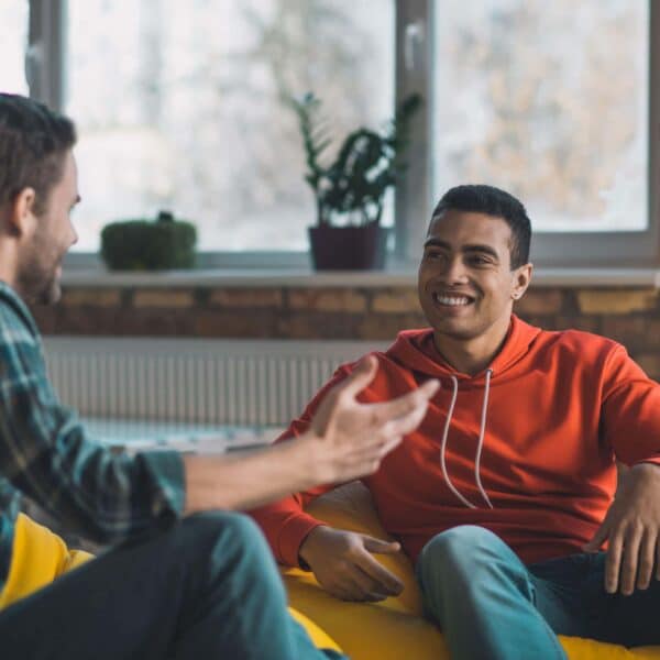 men talk whilst sitting on sofa scaled