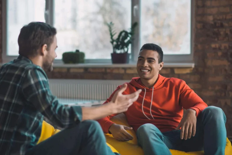 men talk whilst sitting on sofa scaled