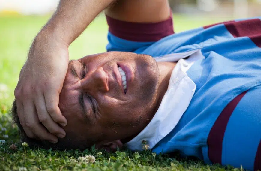 Injured rugby player with eyes closed lying on field