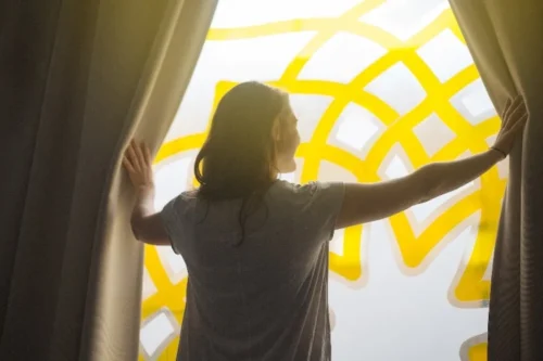 woman draws curatins back