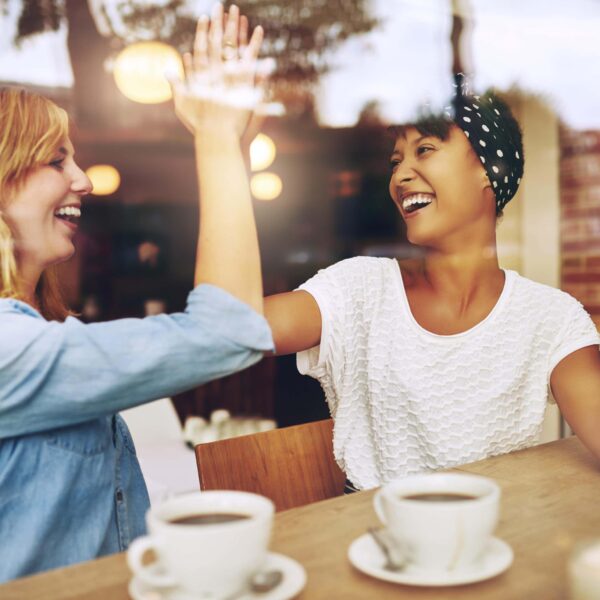 women share a laugh over coffee scaled