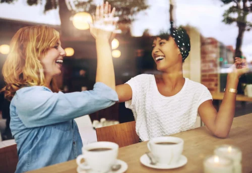 women share a laugh over coffee