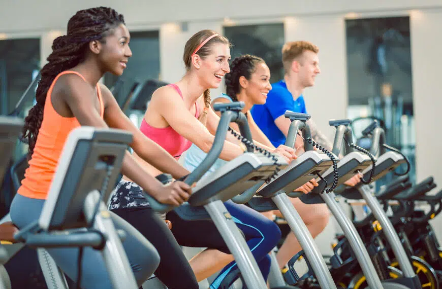 women smiling while cycling on a fitness bicycle during group spinning class at the gym