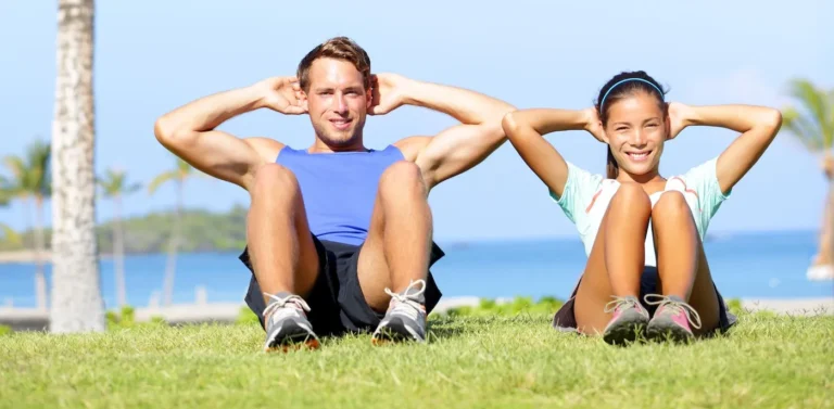 couple performing situps by the sea