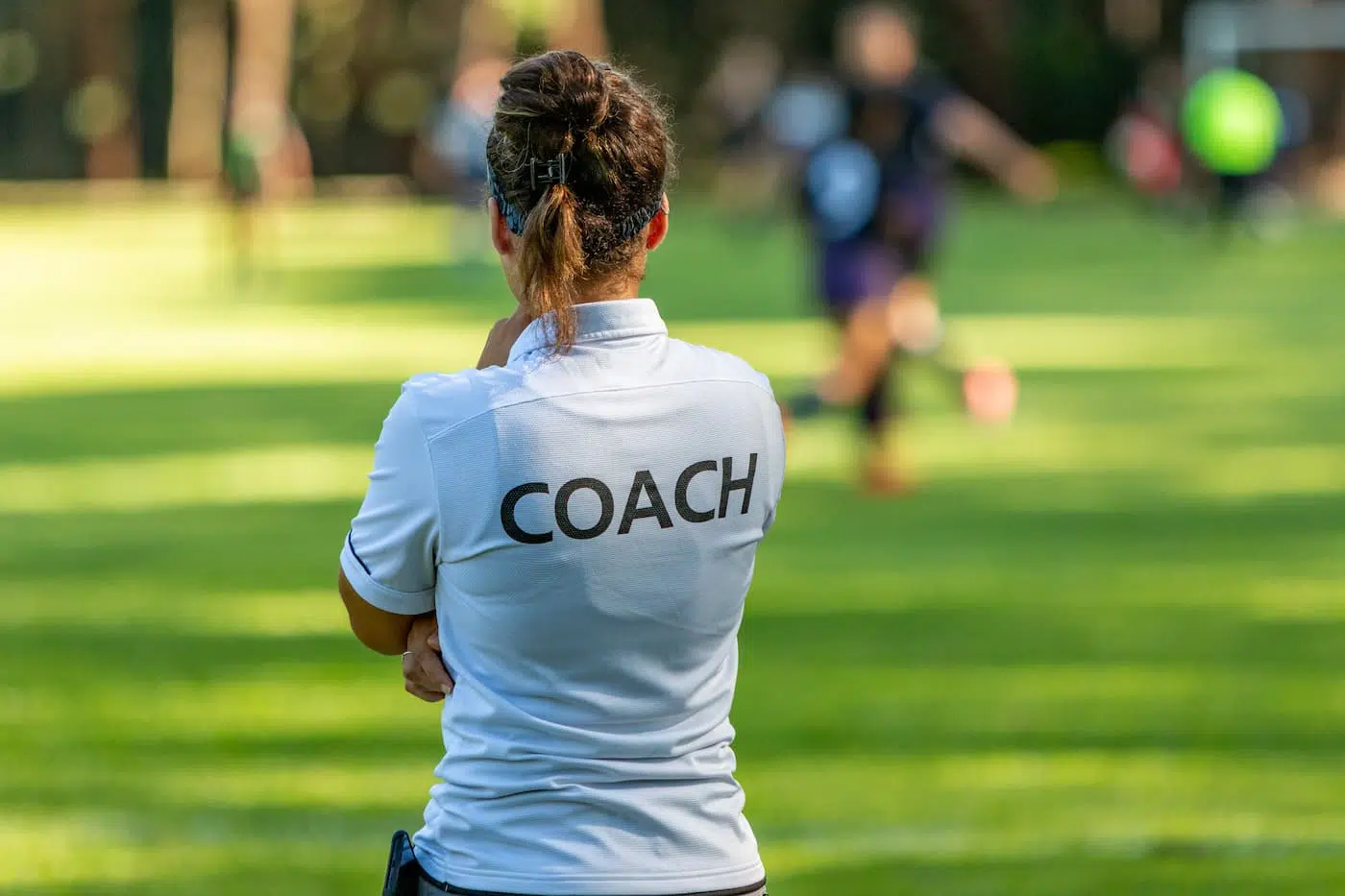 Female sports coach watches from the side