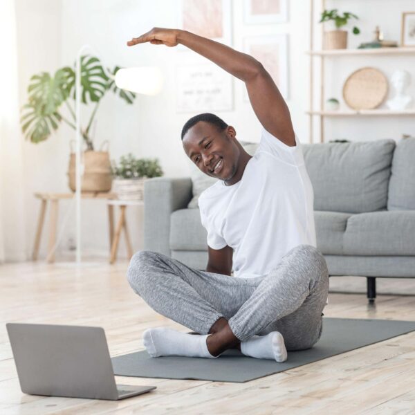 man stretches at home in front of laptop scaled