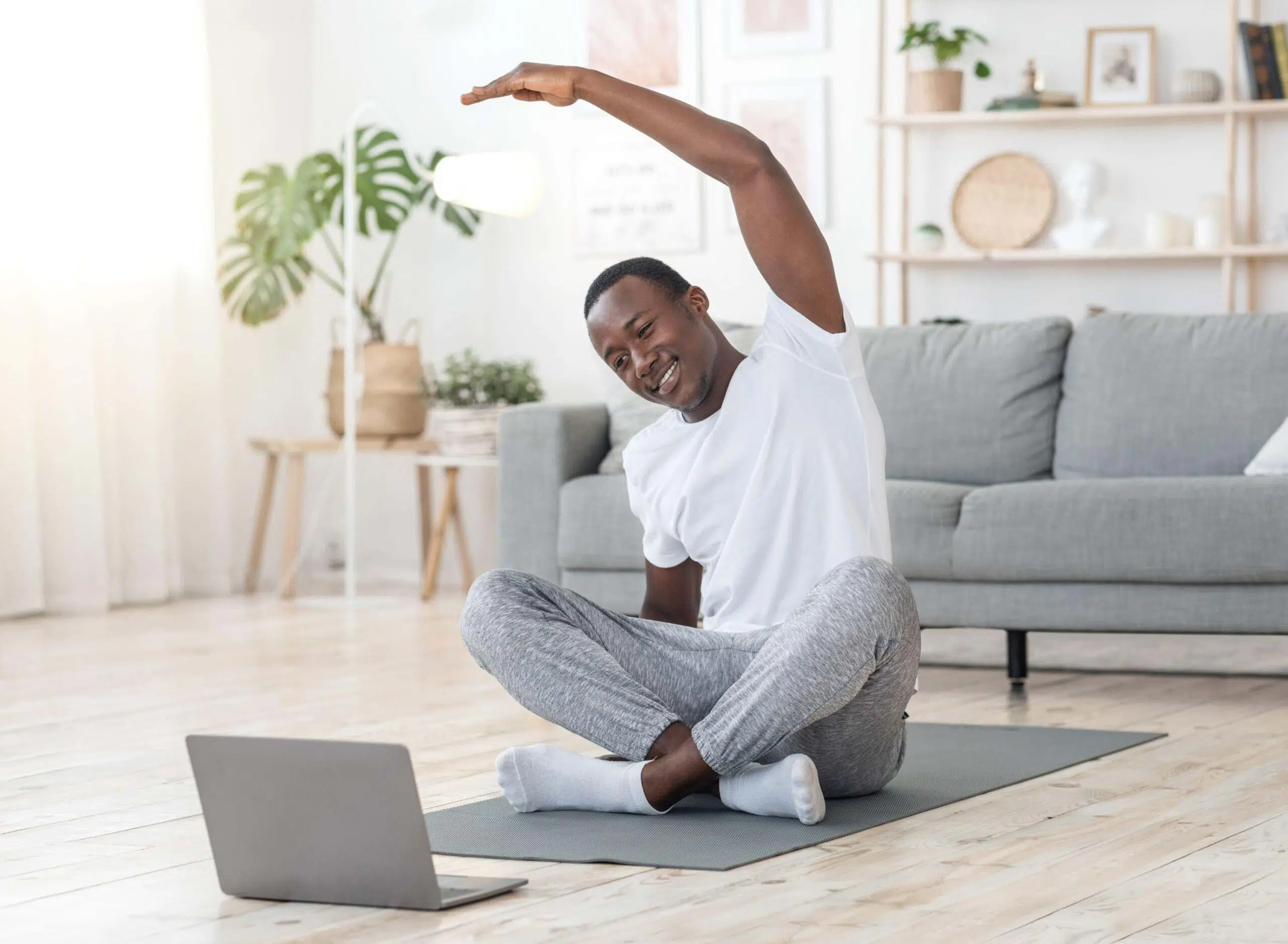 Man stretches at home in front of laptop scaled