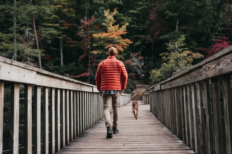 man walks across footbridge with dog