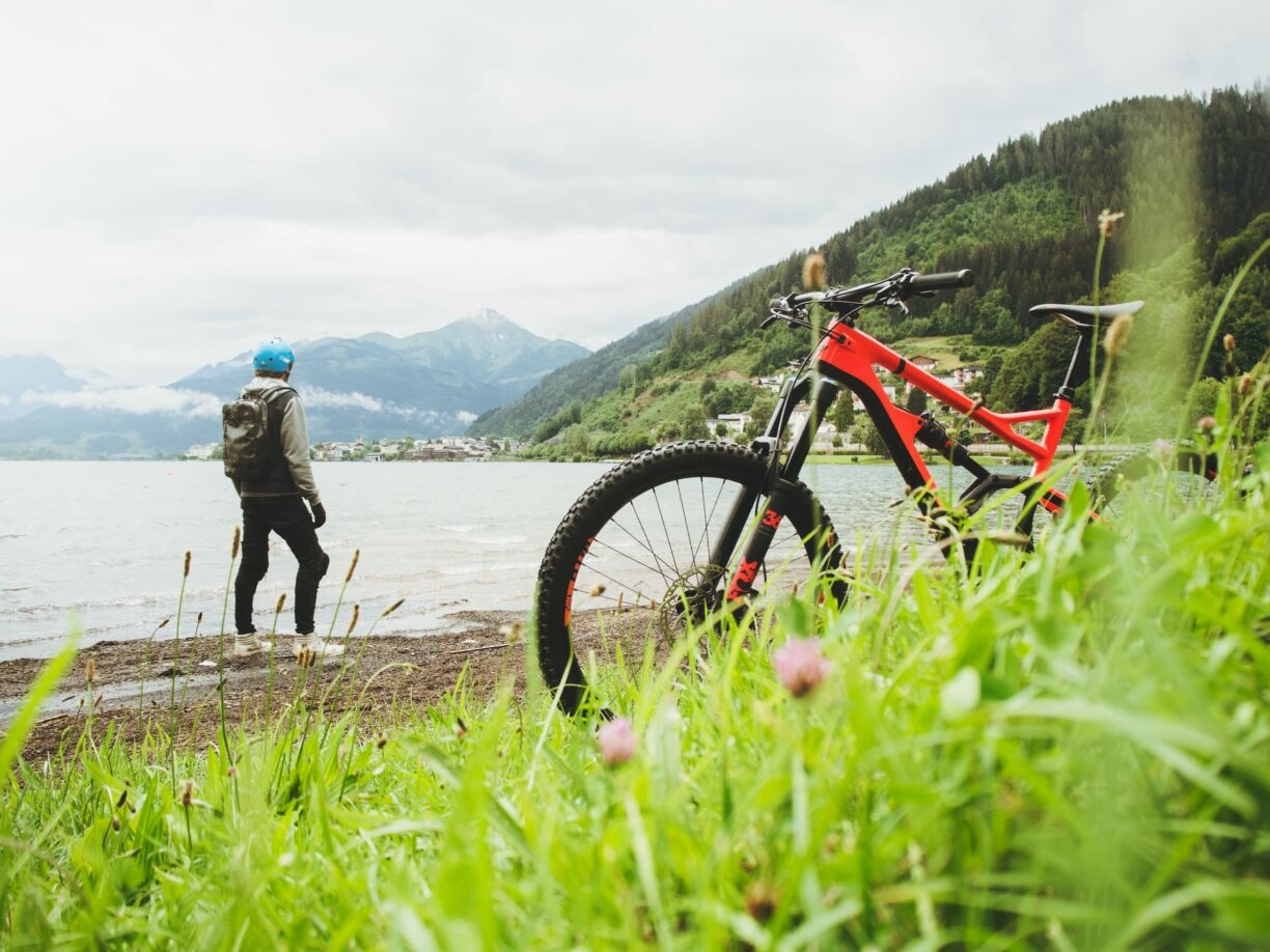 شخص پس از ترک دوچرخه کوهستان به آن سوی دریاچه نگاه می کند
