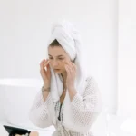 woman applies cream to face