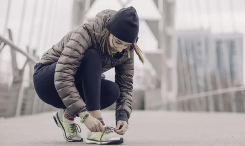 woman bends to tie laces