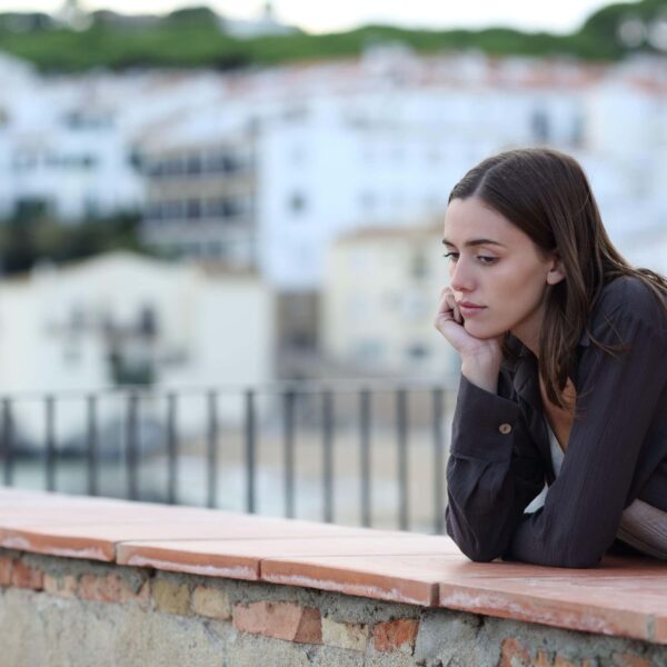 woman looks sadly leaning across a wall scaled