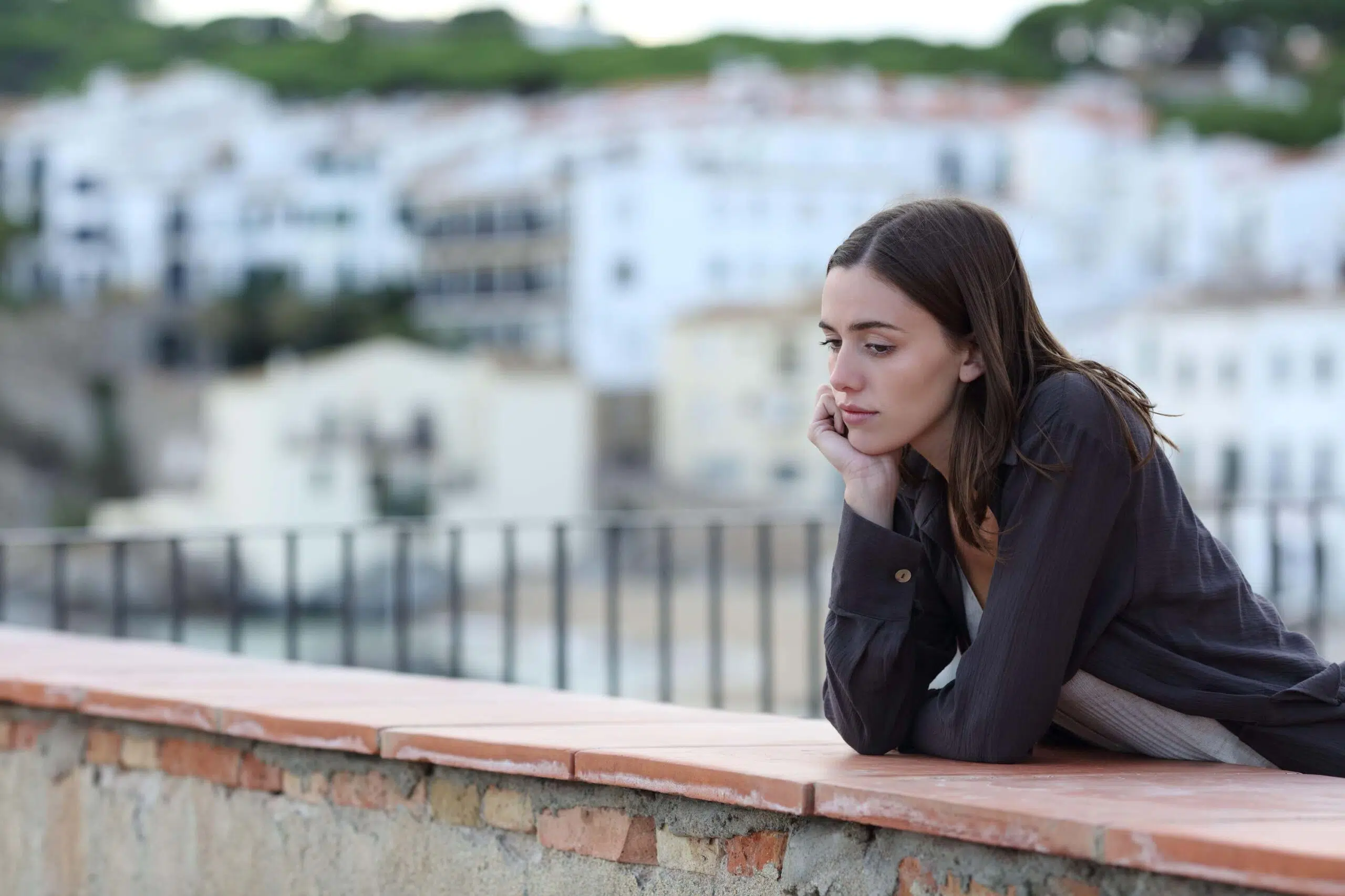 Woman looks sadly leaning across a wall scaled