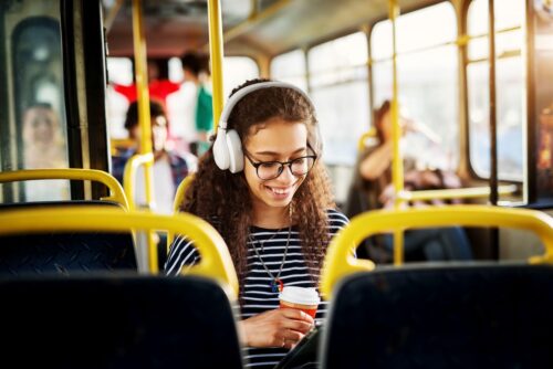 woman smiles at phone whilst commuting on a bus