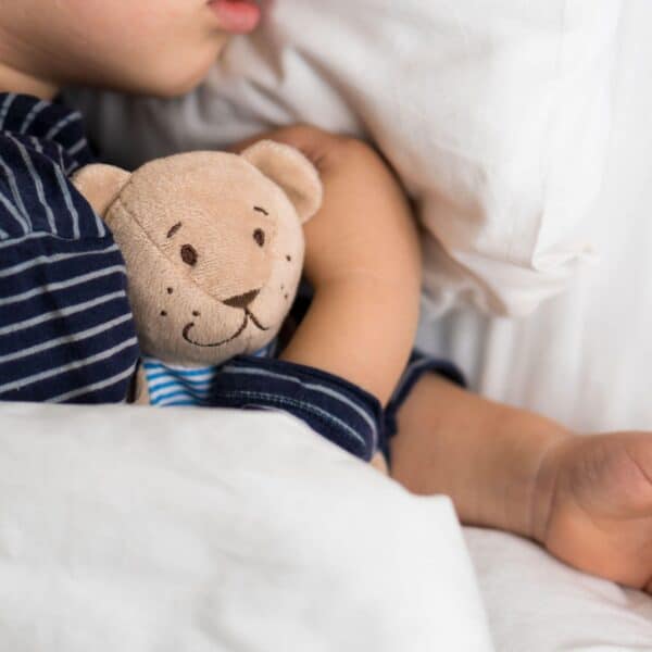 young child cuddles teddy bear scaled