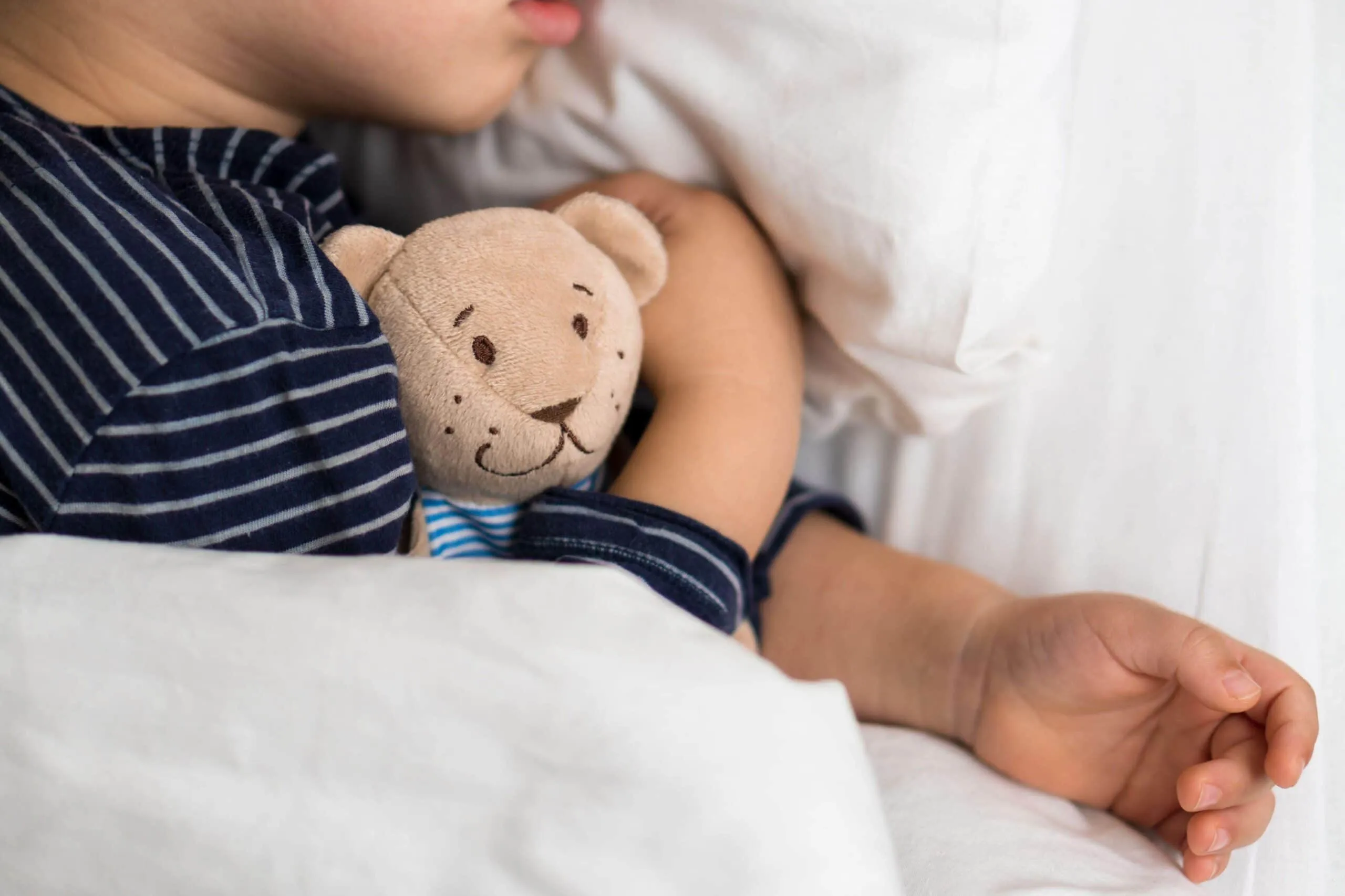 young child cuddles teddy bear scaled