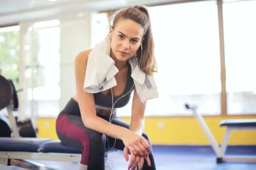 young fit lady sits at the end of bench