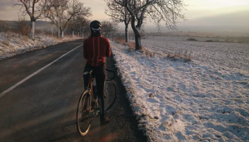 cyclist riding on road surrounded by snow