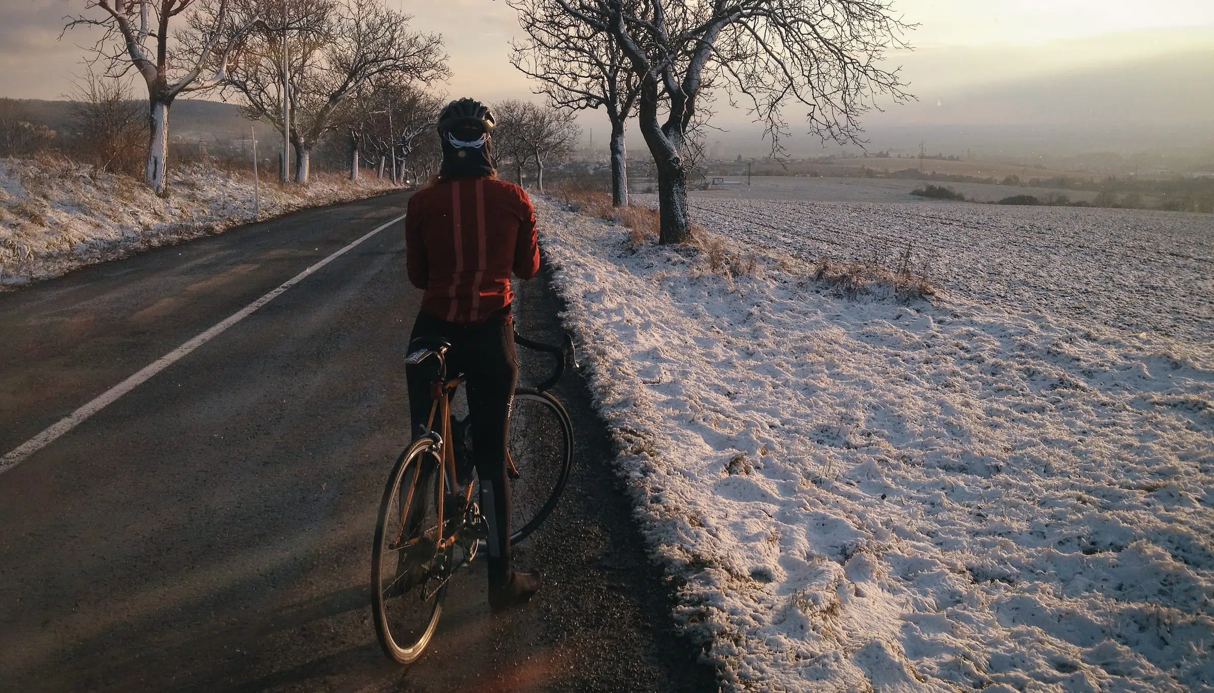 Cyclist riding on road surrounded by snow