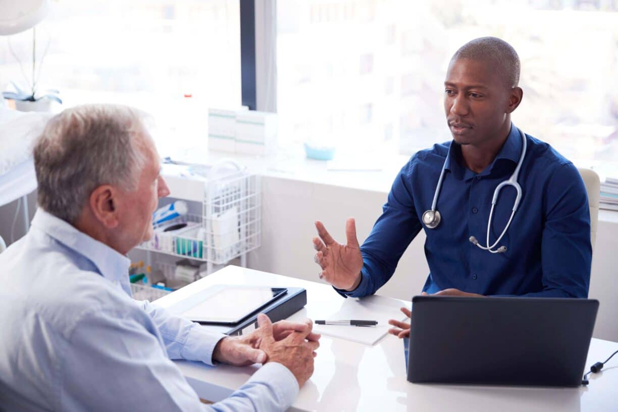 man sits talking with his doctor