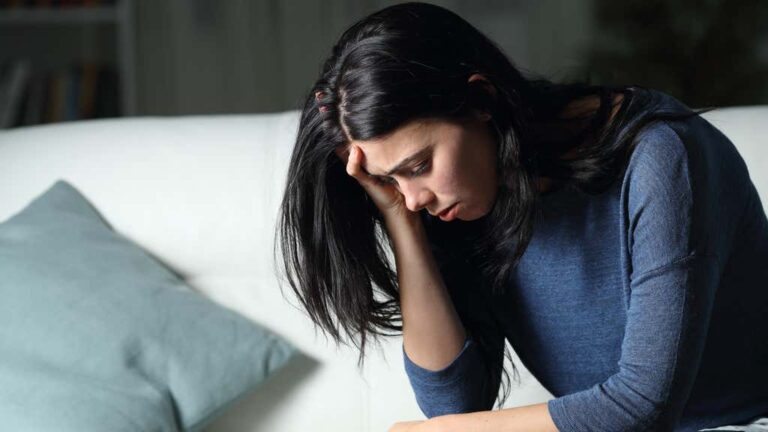 woman holds head in hand