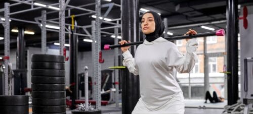 muslim woman lifts heavy weights in gym