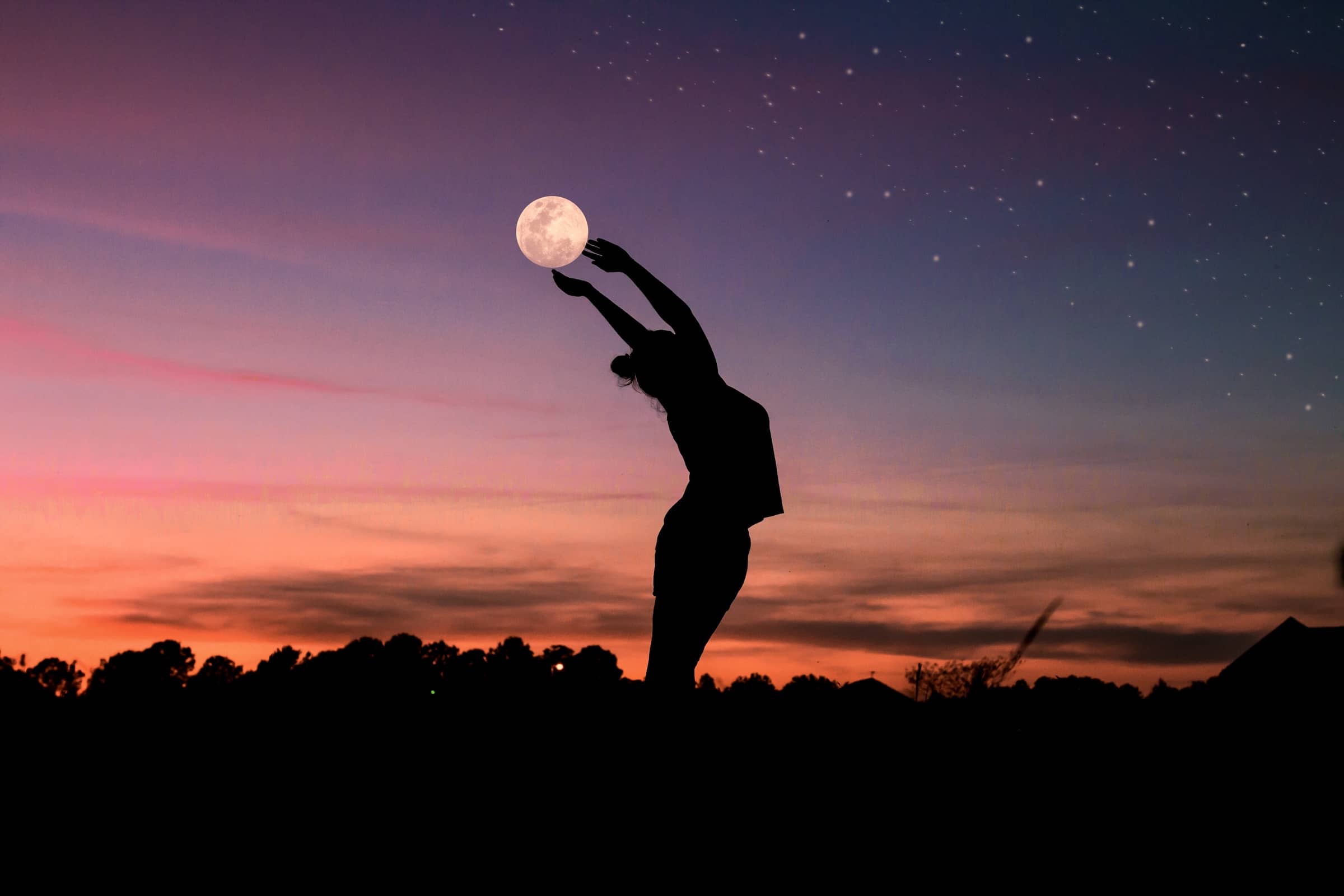 Silhouette of woman bending her back and holding the moon during sunset
