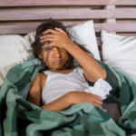 child lays in bed holding head scaled