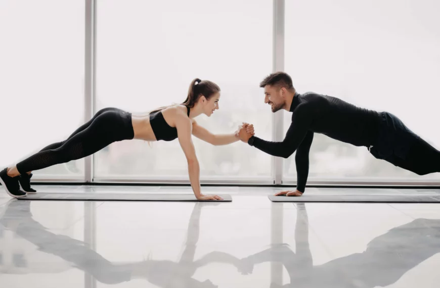 couple hold hands as they hold a plank together scaled