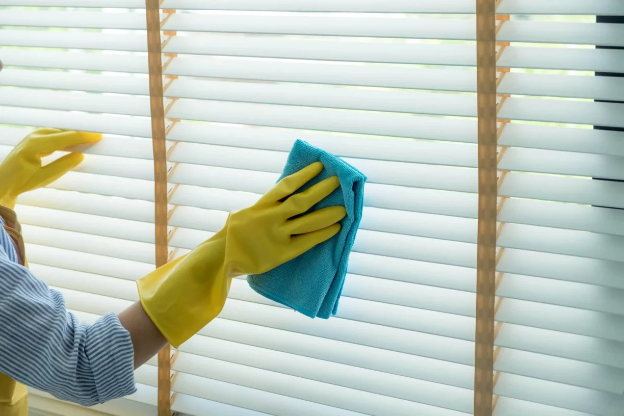 person cleaning blinds