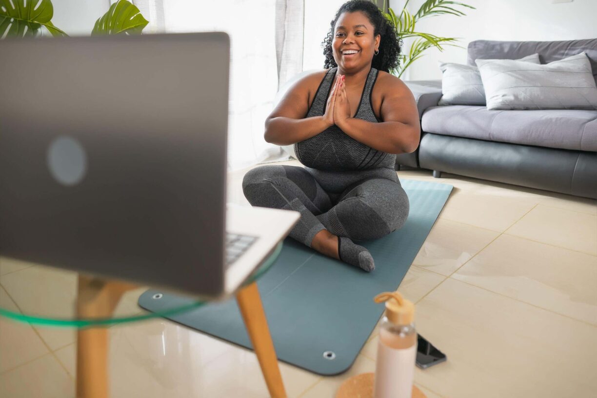 Woman on yoga mat in front of laptop