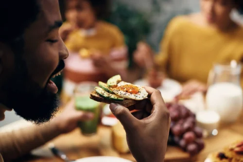 Close up of man eating healthy egg sandwich at home