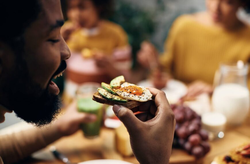 Close up of man eating healthy egg sandwich at home