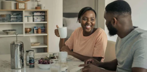 couple smile over drinks at kitchen table scaled