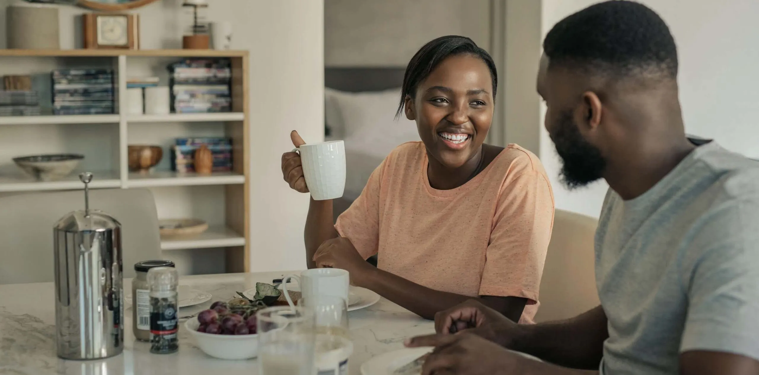 couple smile over drinks at kitchen table scaled