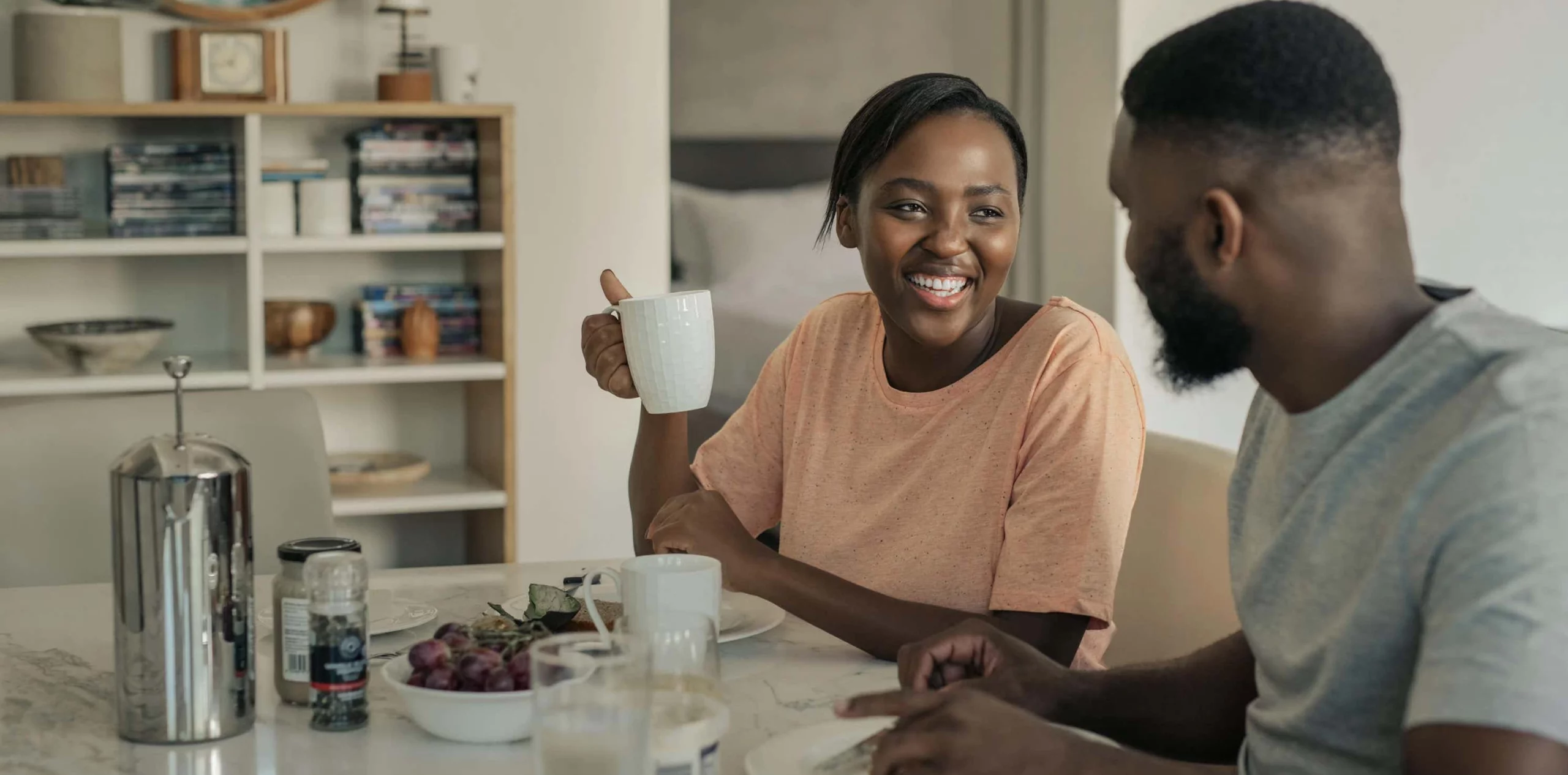 Couple smile over drinks at kitchen table scaled