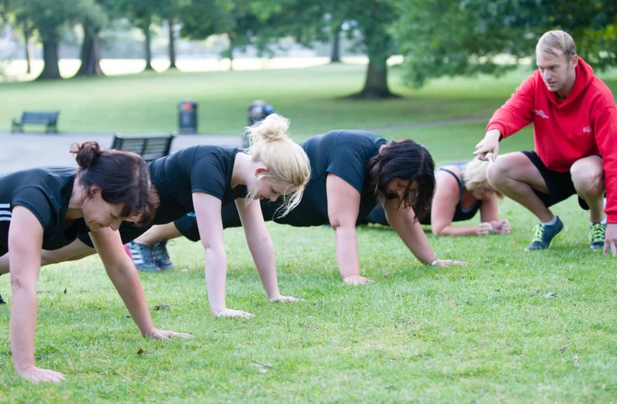 people hold plank position outside in park