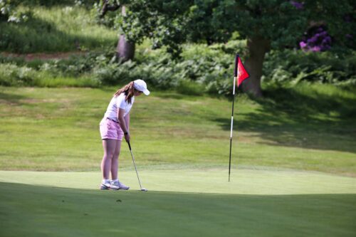 young golfer on green putting