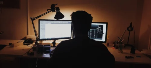 person in darkened room in front of computer