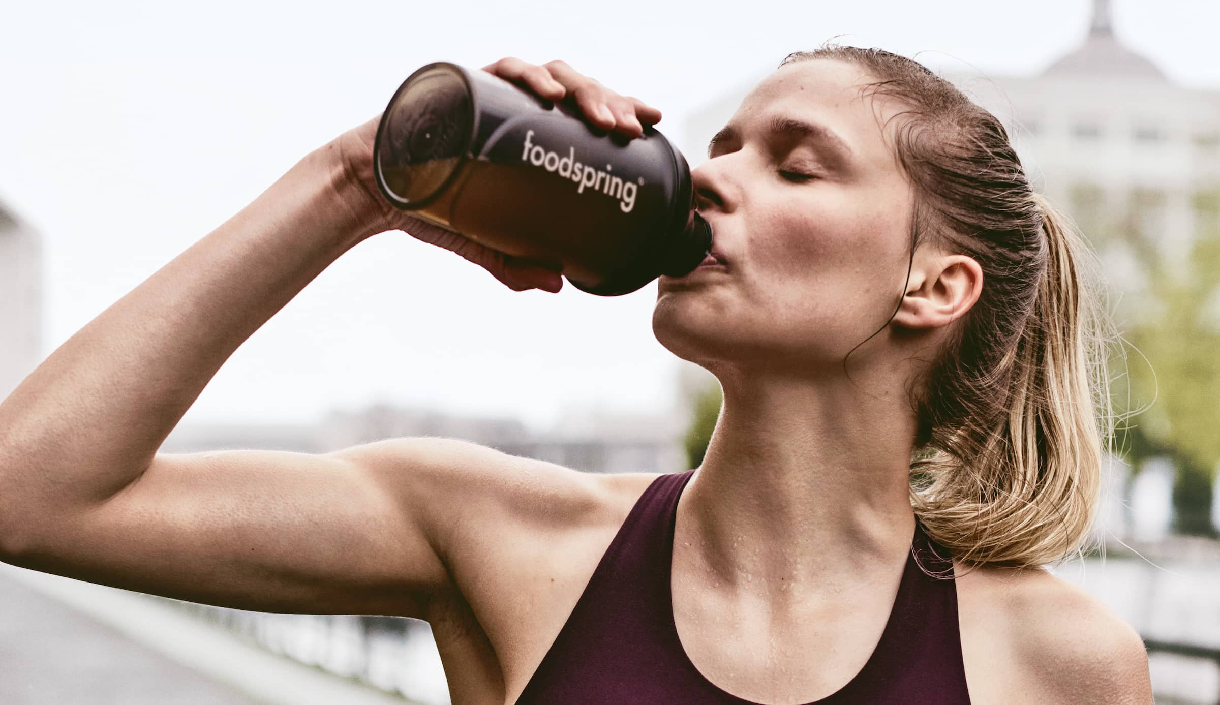 Fitness woman drinks from foodspring bottle