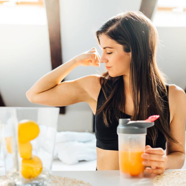 Woman at home drinking orange flavored amino acid vitamin powder