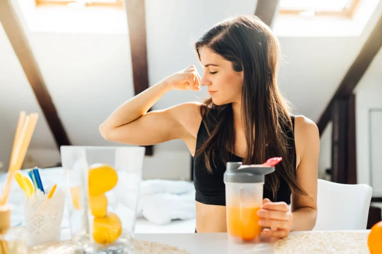 Woman at home drinking orange flavoured amino acid vitamin powder