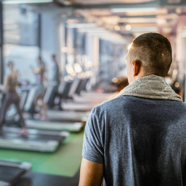 man in gym with sweat on back of t-shirt